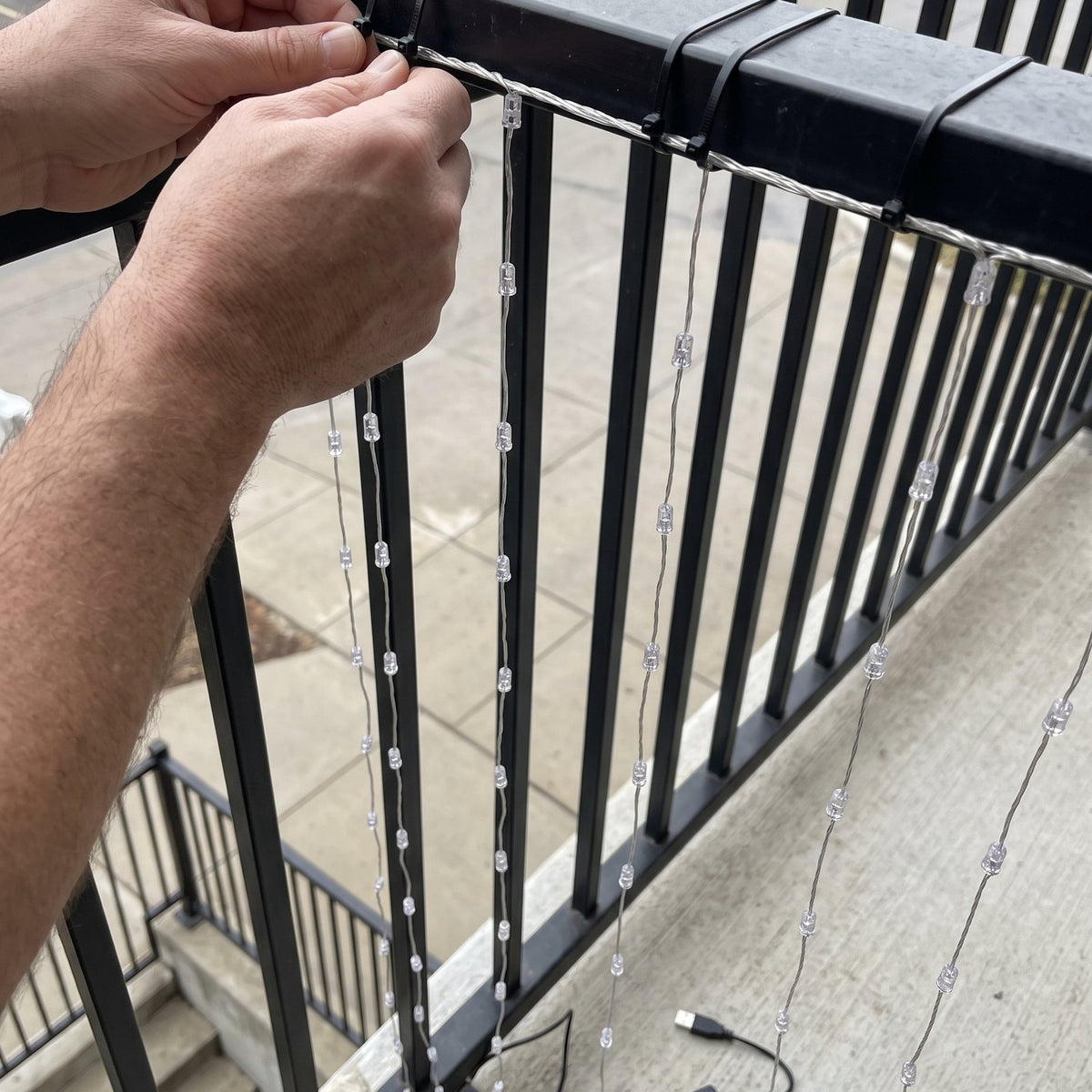 Hands fixing the curtain to a balcony railing, no drilling