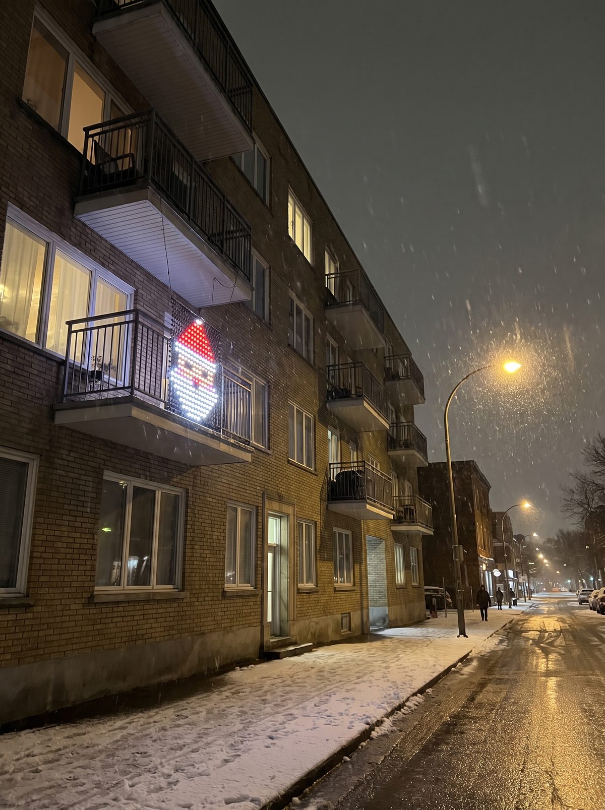A balcony with Santa in LED dots on a snowy night
